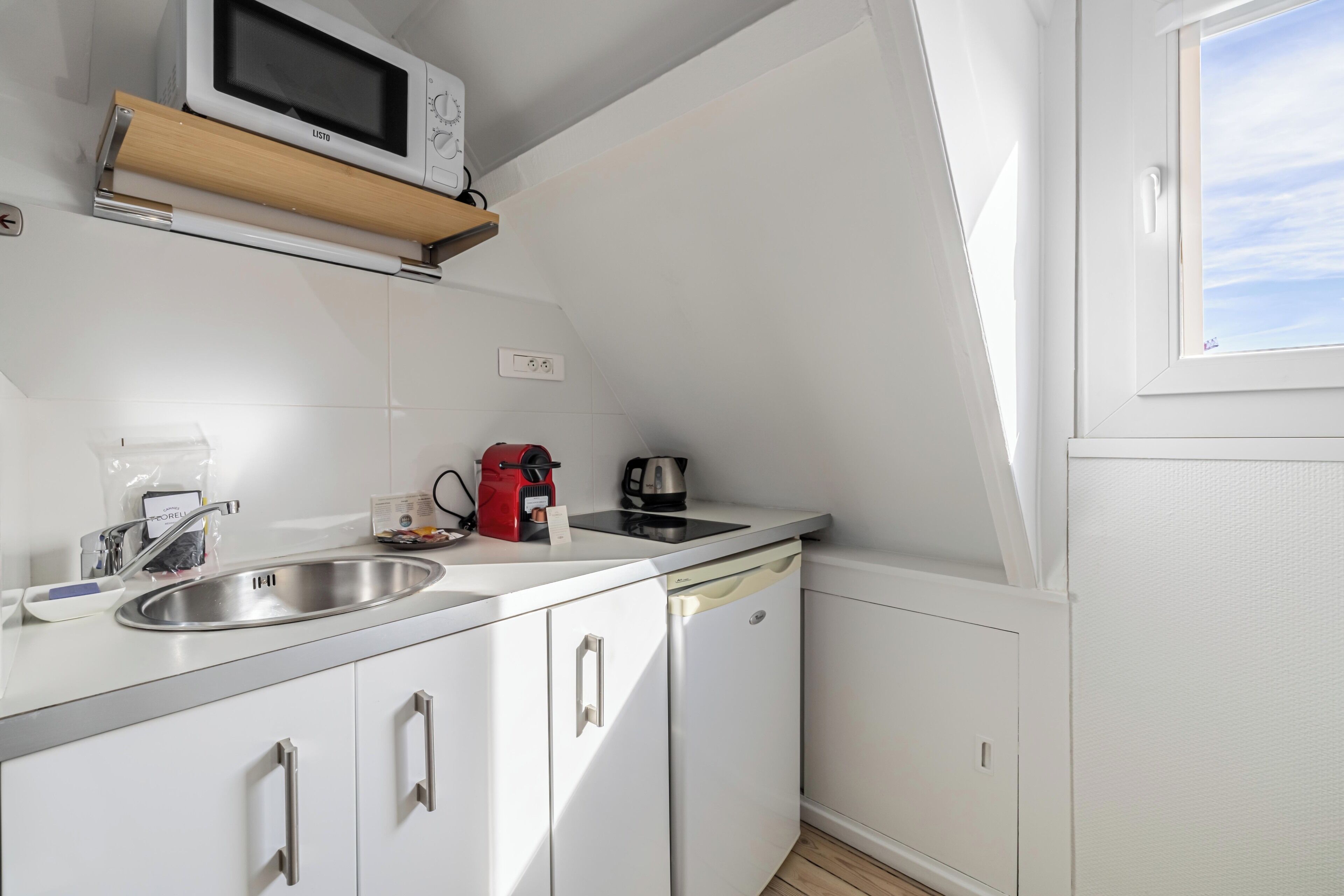A compact kitchen with a microwave, coffee maker, and sink.
