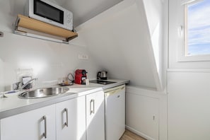 A compact kitchen with a microwave, coffee maker, and sink.
