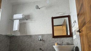 Un bagno moderno con uno specchio grande, un lavabo con bacino a vista, un portasciugamani e una zona doccia.