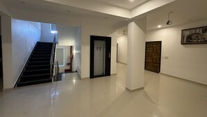 Un'ampia sala con una scala, una porta in legno e un quadro appeso al muro.