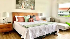 Ein Hotelzimmer mit Bett, Nachttischen, einer Schlafcouch, einem Fenster und einem Wandbild.