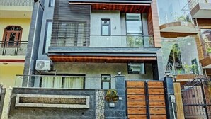 A modern two-story house with a wooden facade, large windows, and a gated entrance. - Kashvi Residency (Greater Noida)