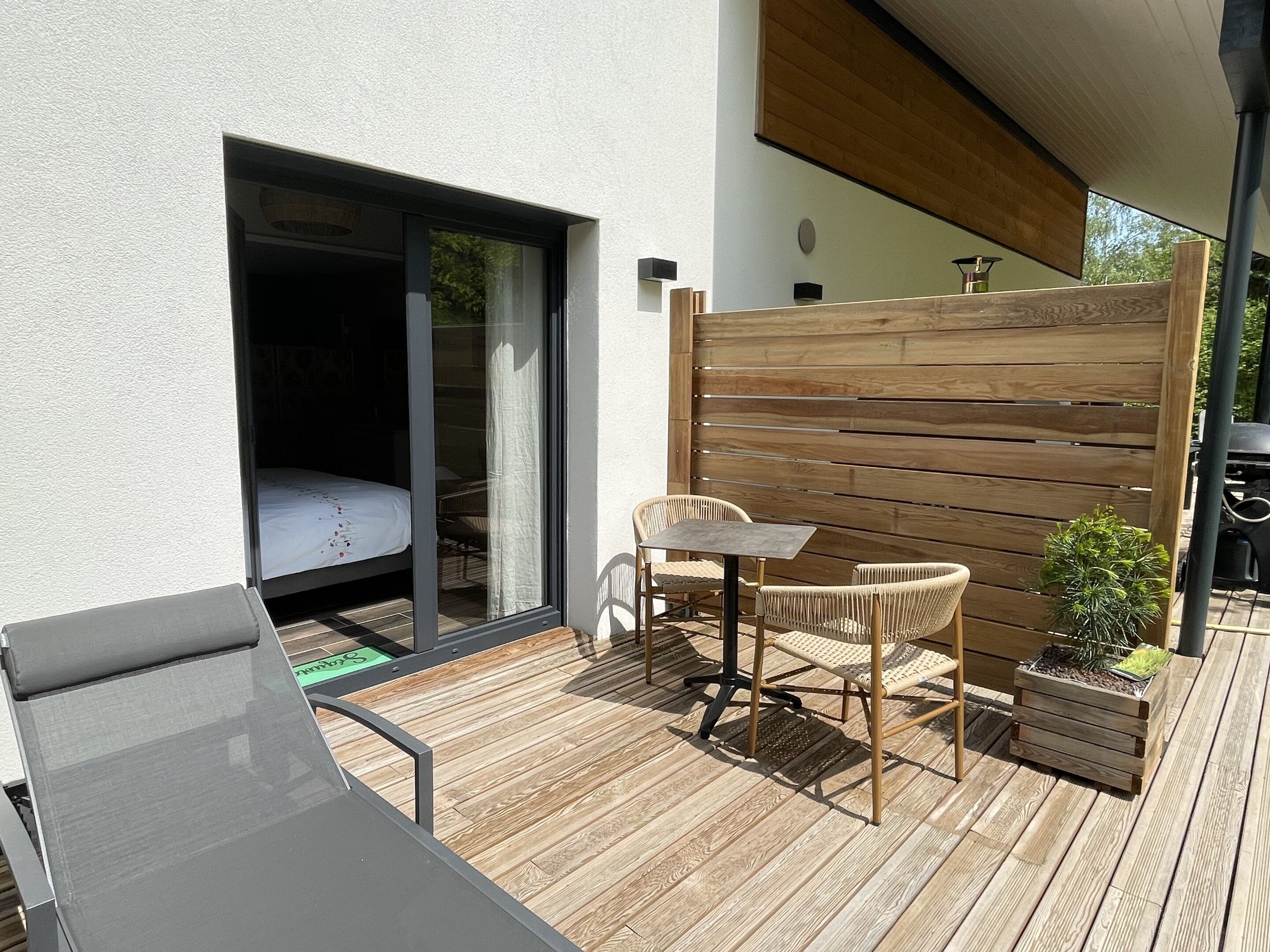 A patio with a table and chairs, a small garden, and a sliding glass door leading to a bedroom.