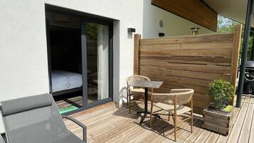 A patio with a table and chairs, a small garden, and a sliding glass door leading to a bedroom.