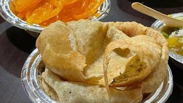 A table with various food items including fried snacks and a bowl of orange-colored sweets.