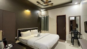 A modern hotel room with a bed, a desk, a chair, a ceiling fan, and a wardrobe. - The White Canyon (Varanasi)