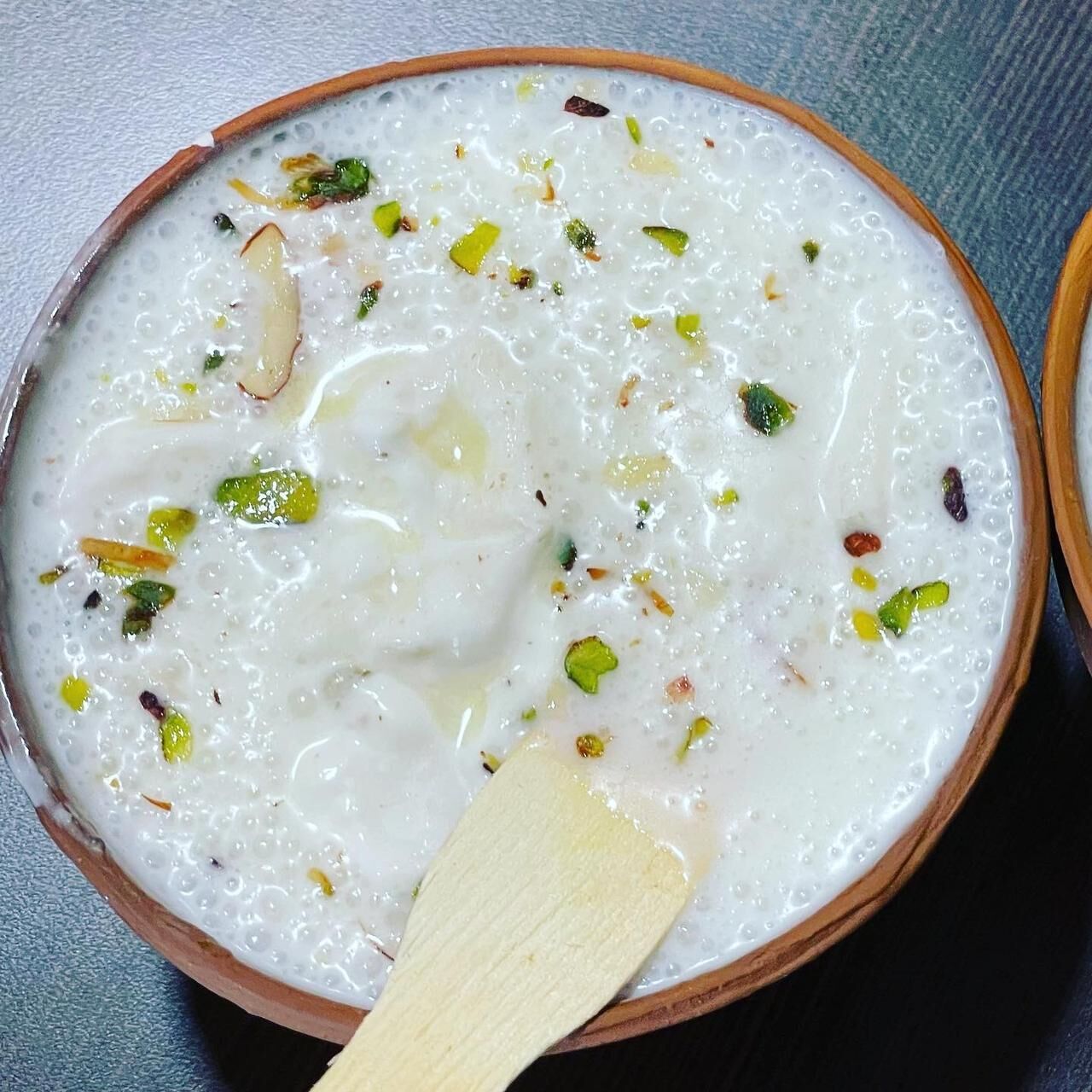 A bowl of creamy dessert with nuts and raisins.