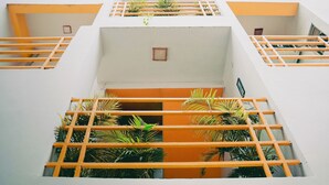 A multi-level building with balconies and a central courtyard with plants. - The White Canyon (Varanasi)