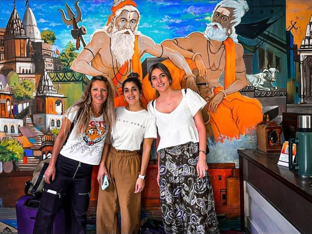 A group of people in a room with a mural of a cityscape and religious figures.