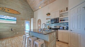 A kitchen with a large island, white cabinets, and a wooden ceiling. - Shared Pool w/ Bay Views, Boat Dock | Fishing | Big Slough by AvantStay (Corpus Christi)