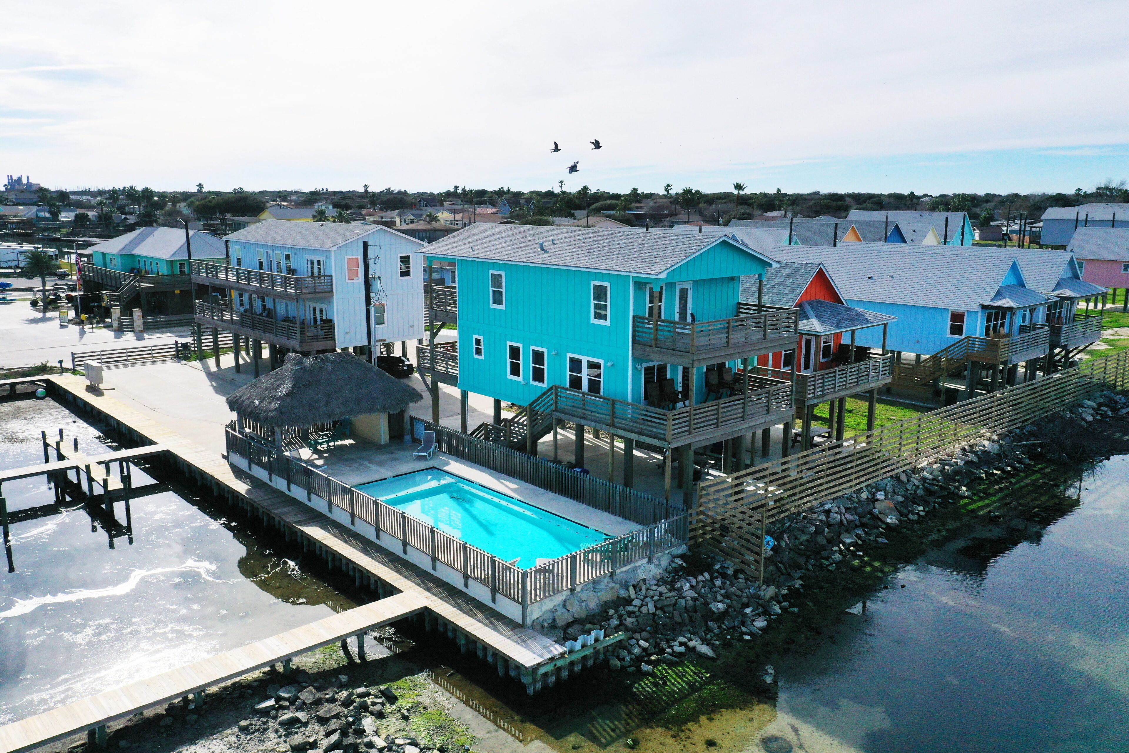A waterfront property with multiple blue buildings, a swimming pool, and a dock.