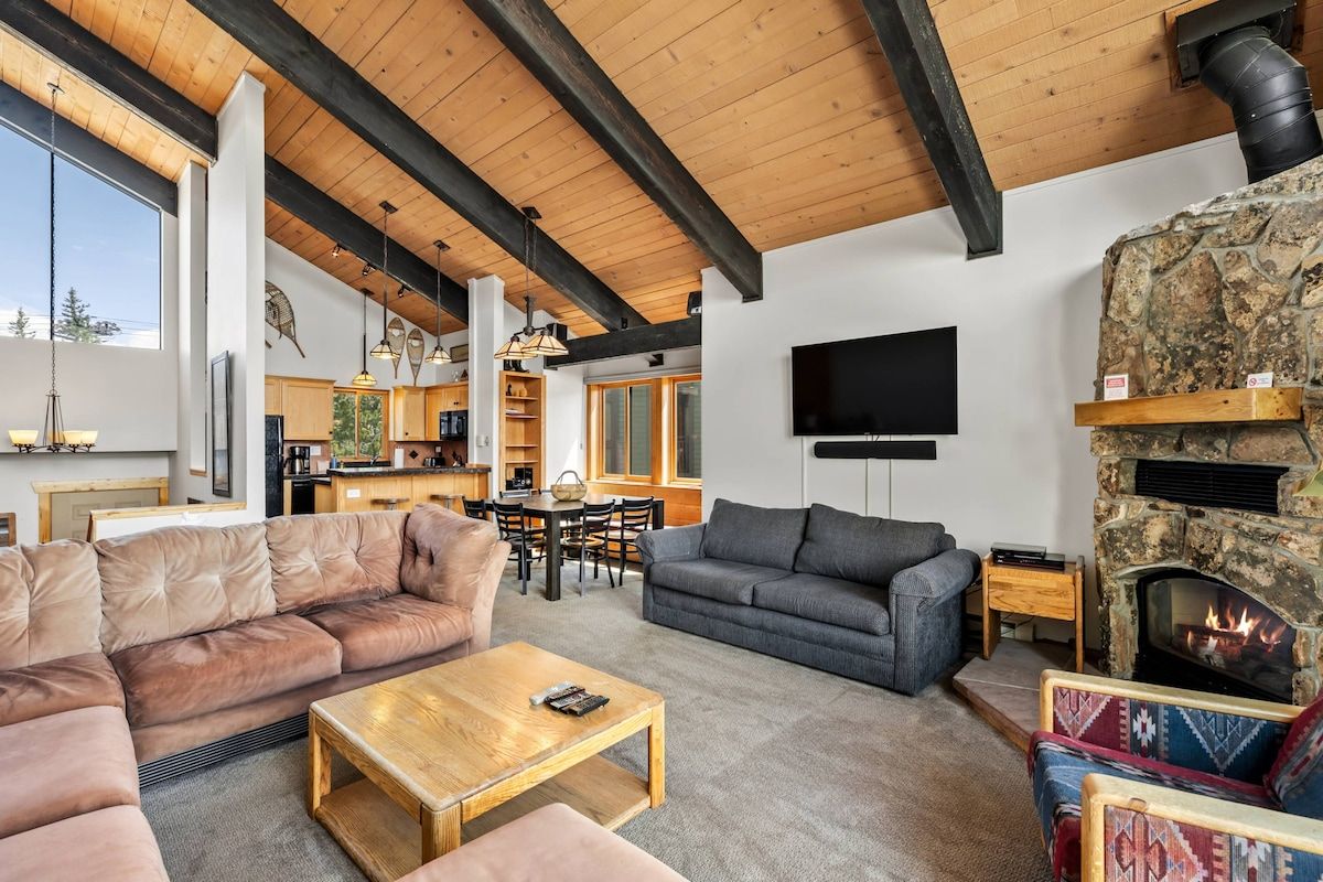 A spacious living area with a stone fireplace, leather sofas, and a dining area with wooden furniture.