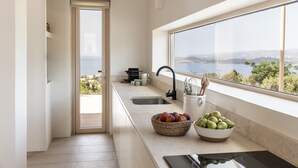 Een moderne keuken met een groot raam, een spoelbak en een fruitschaal op het aanrecht.