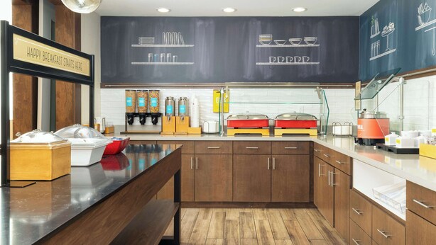 A breakfast area with a wooden counter, a chalkboard menu, and various breakfast items. - Hampton Inn & Suites Porter Ranch Los Angeles (Porter Ranch)