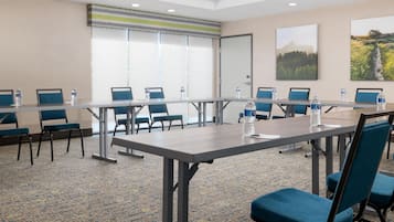 A conference room with a long table, blue chairs, and water bottles.