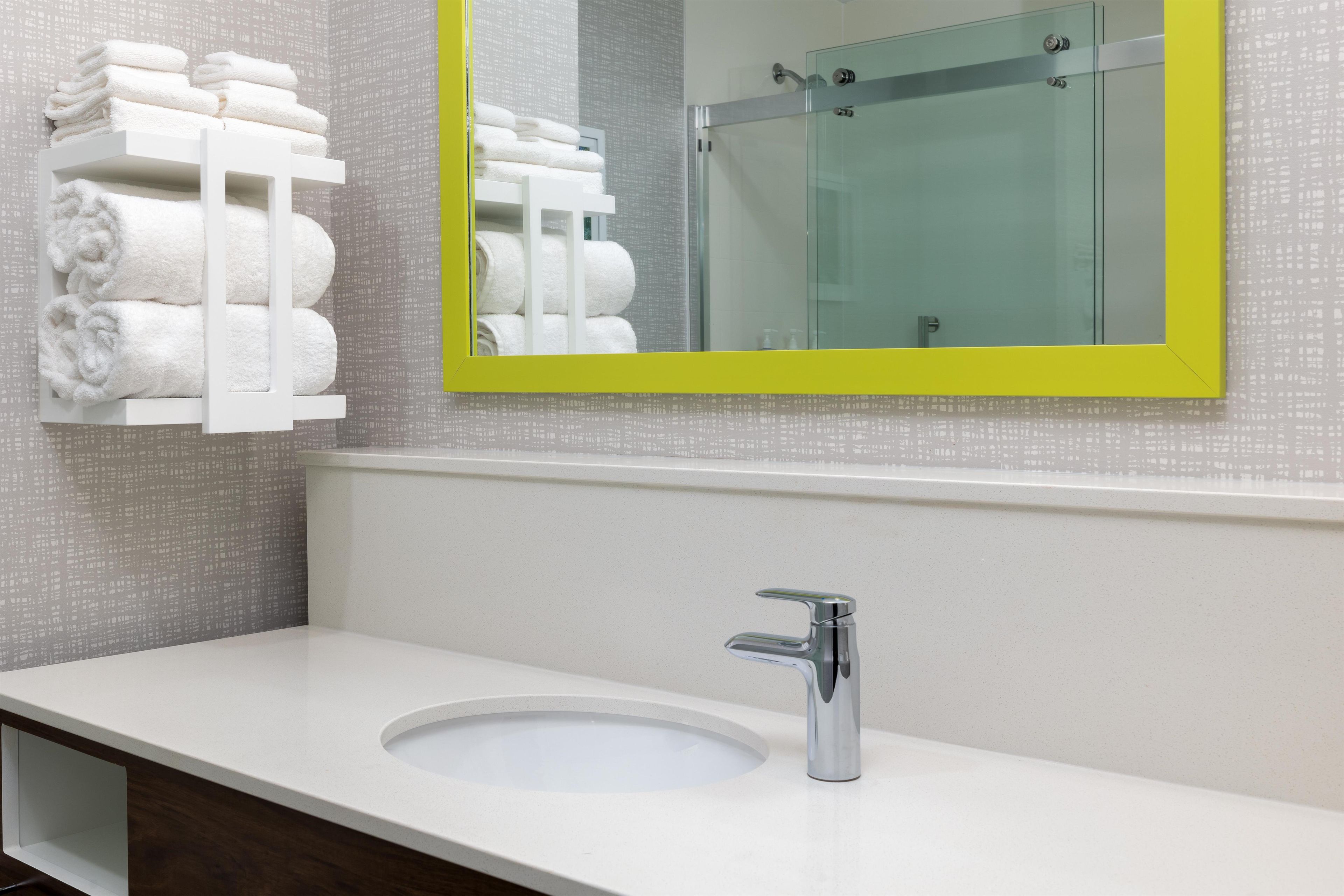 A bathroom with a white sink, a chrome faucet, and a mirror with a yellow frame.