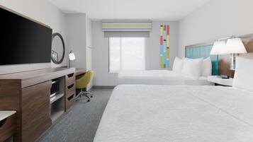A hotel room with a large bed, a desk with a flat-screen TV, a chair, a bedside table with a lamp, and a window with a view.
