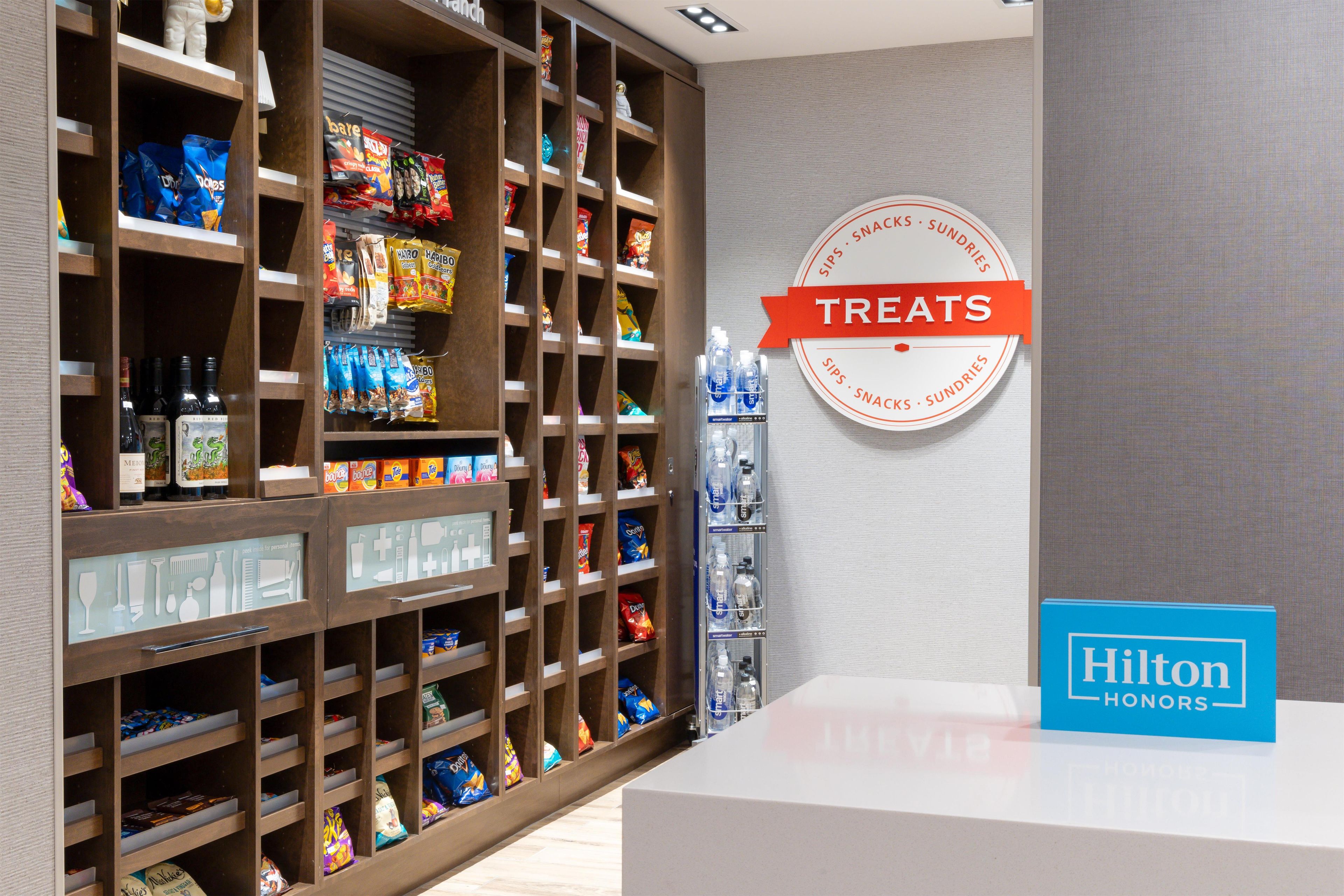 Un mini-bar d’hôtel contenant des en-cas, des boissons et des articles de toilette.