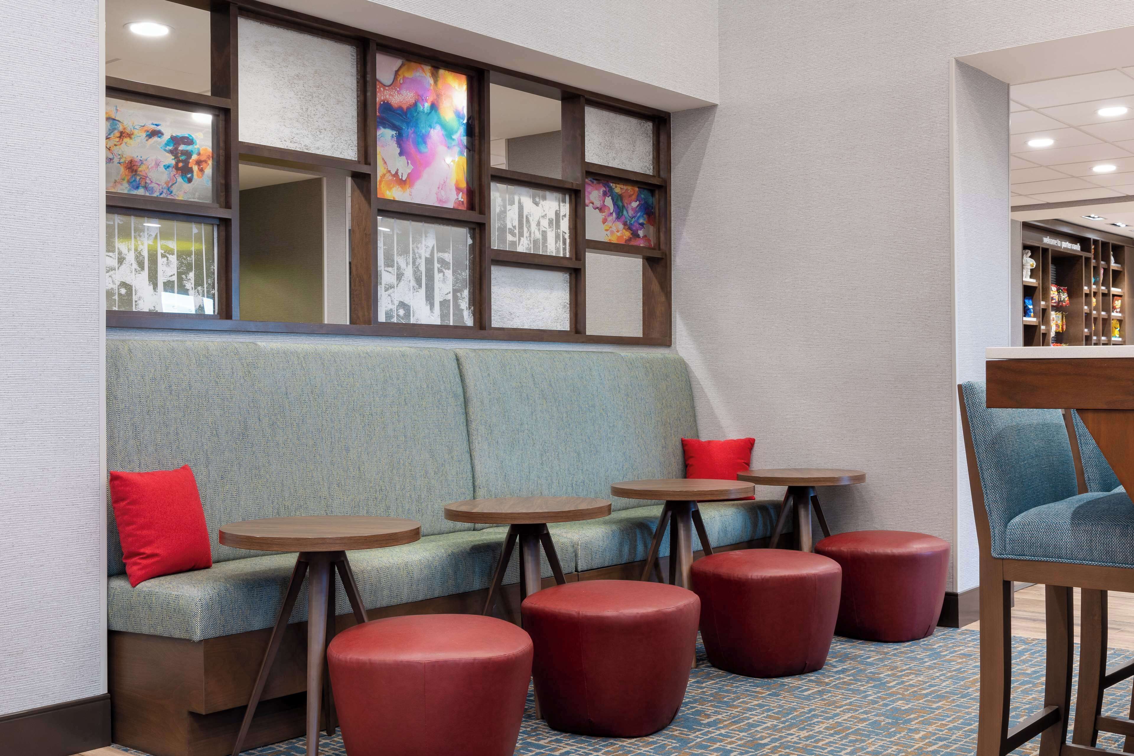 A seating area with a sofa, red cushions, and round tables.