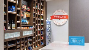 A hotel lobby with a snack and sundries display, a water dispenser, and a Hilton Honors sign. - Hampton Inn & Suites Porter Ranch Los Angeles (Porter Ranch)