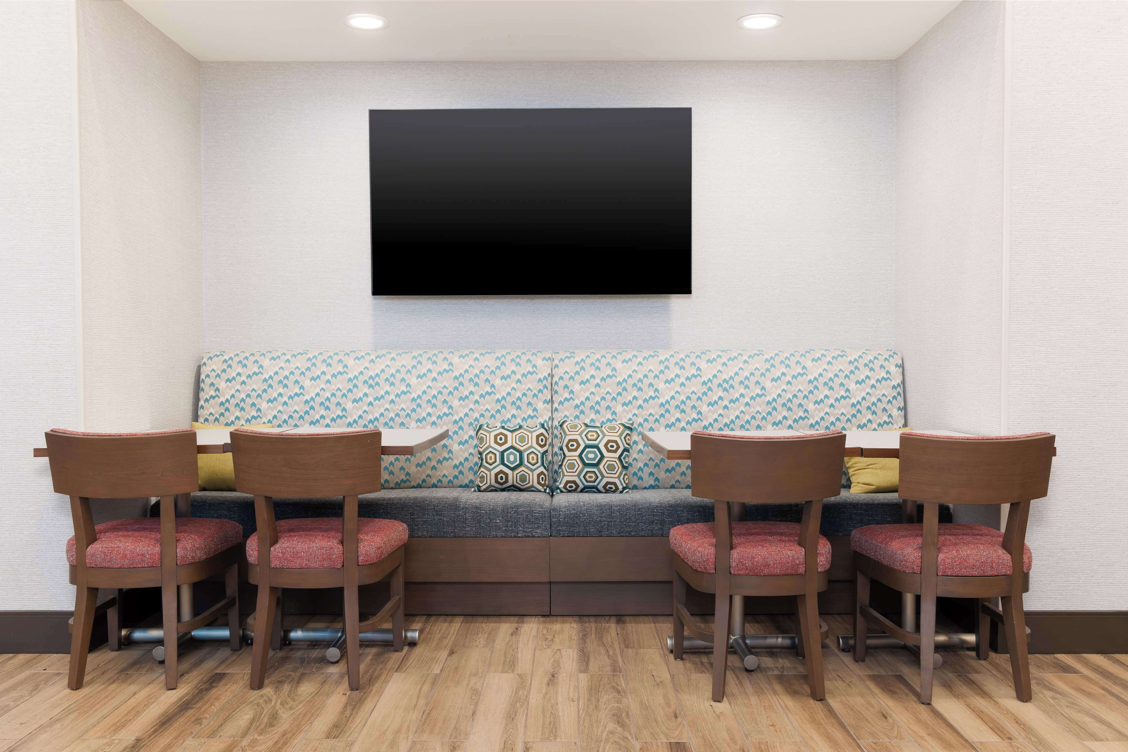 A seating area with a sofa, four chairs, and a flat-screen TV mounted on the wall.