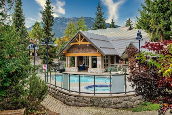 A lodge with a pool, surrounded by trees and mountains.