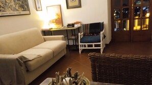 Un salon avec un canapé, une table sur laquelle se trouve un vase rempli de branches, un fauteuil et une lampe.
