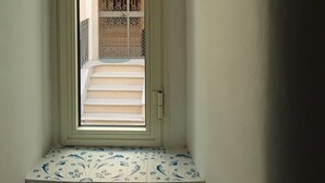 Un escalier étroit menant à une porte ornée d’un vitrail décoratif.