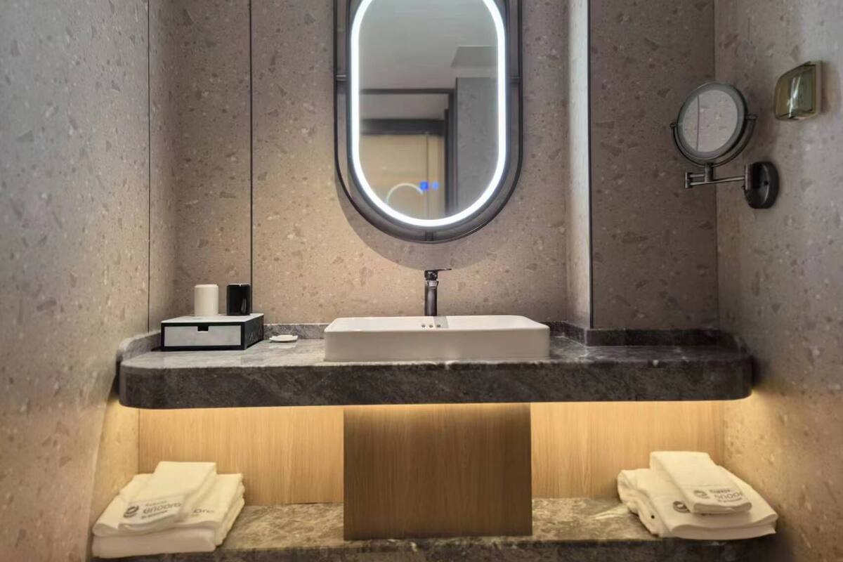 A modern bathroom with a marble countertop, a sink, a mirror, and two towels on the floor.