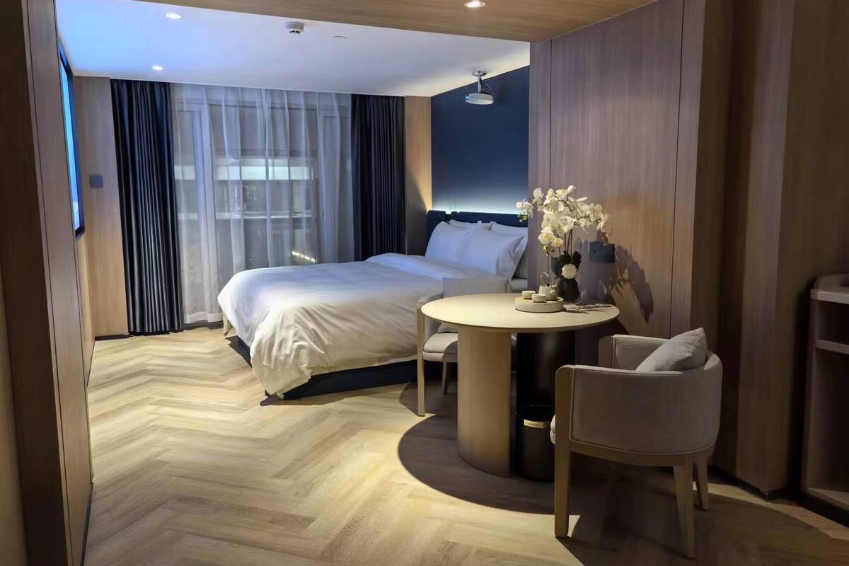 A hotel room with a bed, a round table, and a chair.