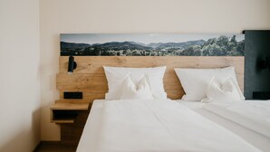 A neatly made bed with white linens, a wooden headboard, and a nightstand with a phone. - Gemütliche Ferienwohnung Hochfelln, 40qm, Balkon (Traunstein)