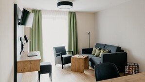 A modern living room with a sofa, chairs, a coffee table, a desk with a laptop, and a floor lamp. - Gemütliche Ferienwohnung Hochfelln, 40qm, Balkon (Traunstein)