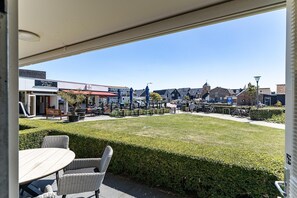 A patio area with tables and chairs, a view of a town with buildings and a church, and a clear sky.