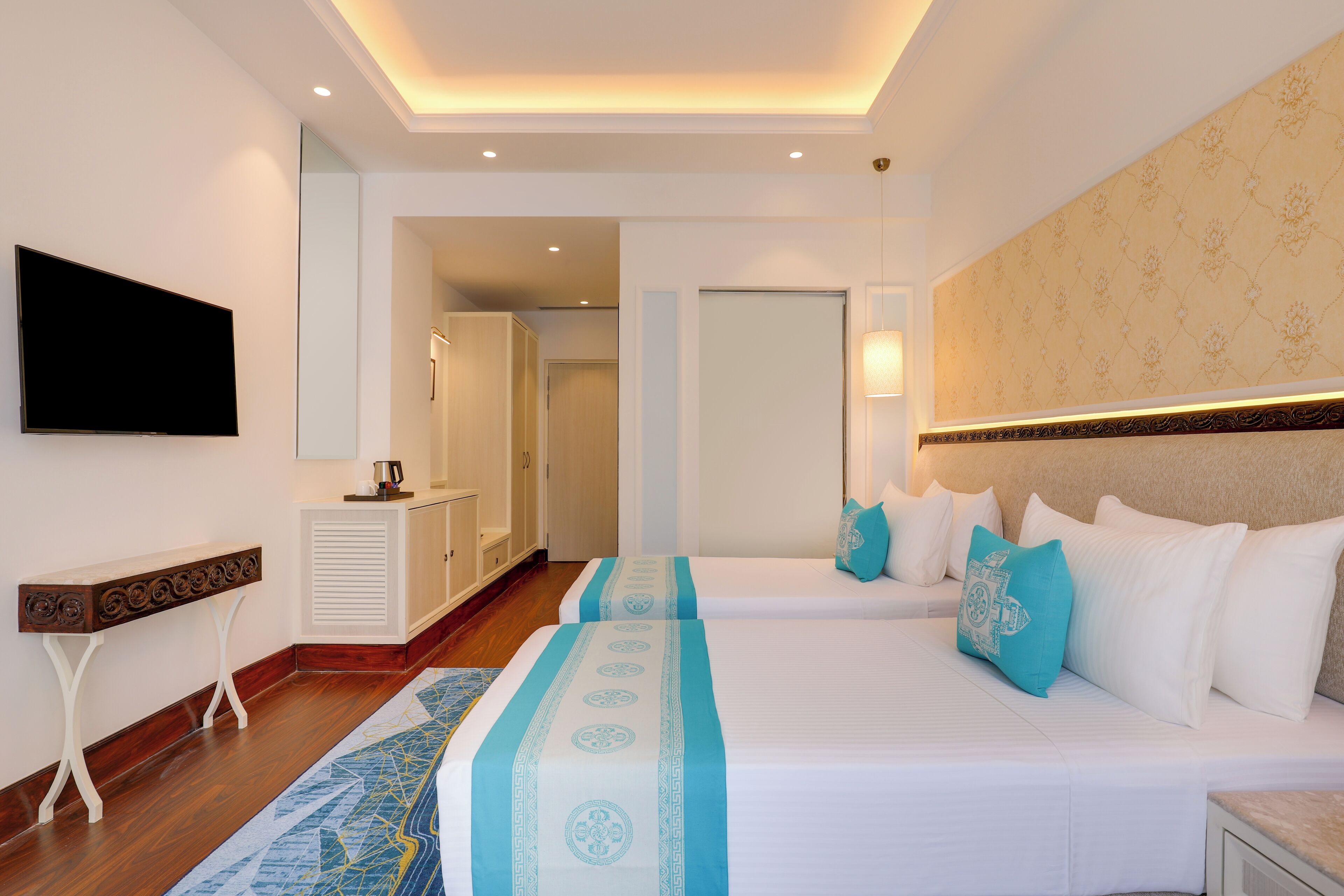 A hotel room with two beds, a TV, a desk, and a mirror.