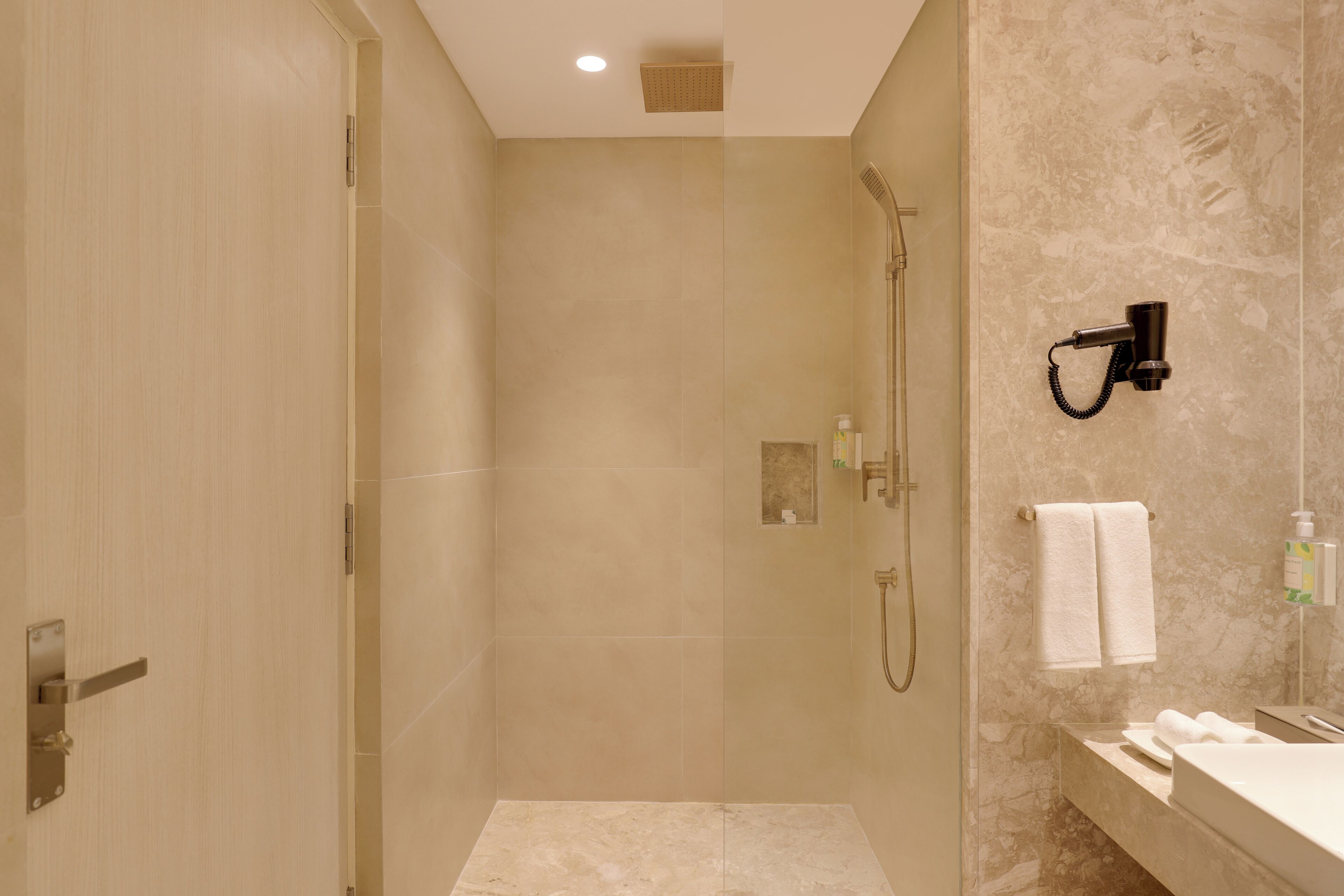A modern bathroom with a glass-enclosed shower, a vanity with a mirror, and a towel rack.