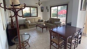 A spacious living area with a large sofa set, a dining table with chairs, and a coffee table. There is a decorative hat stand and a chandelier. - Villa Ariadni - Luxurious Villa with Spectacular Views and Private Pool! (Pissouri)