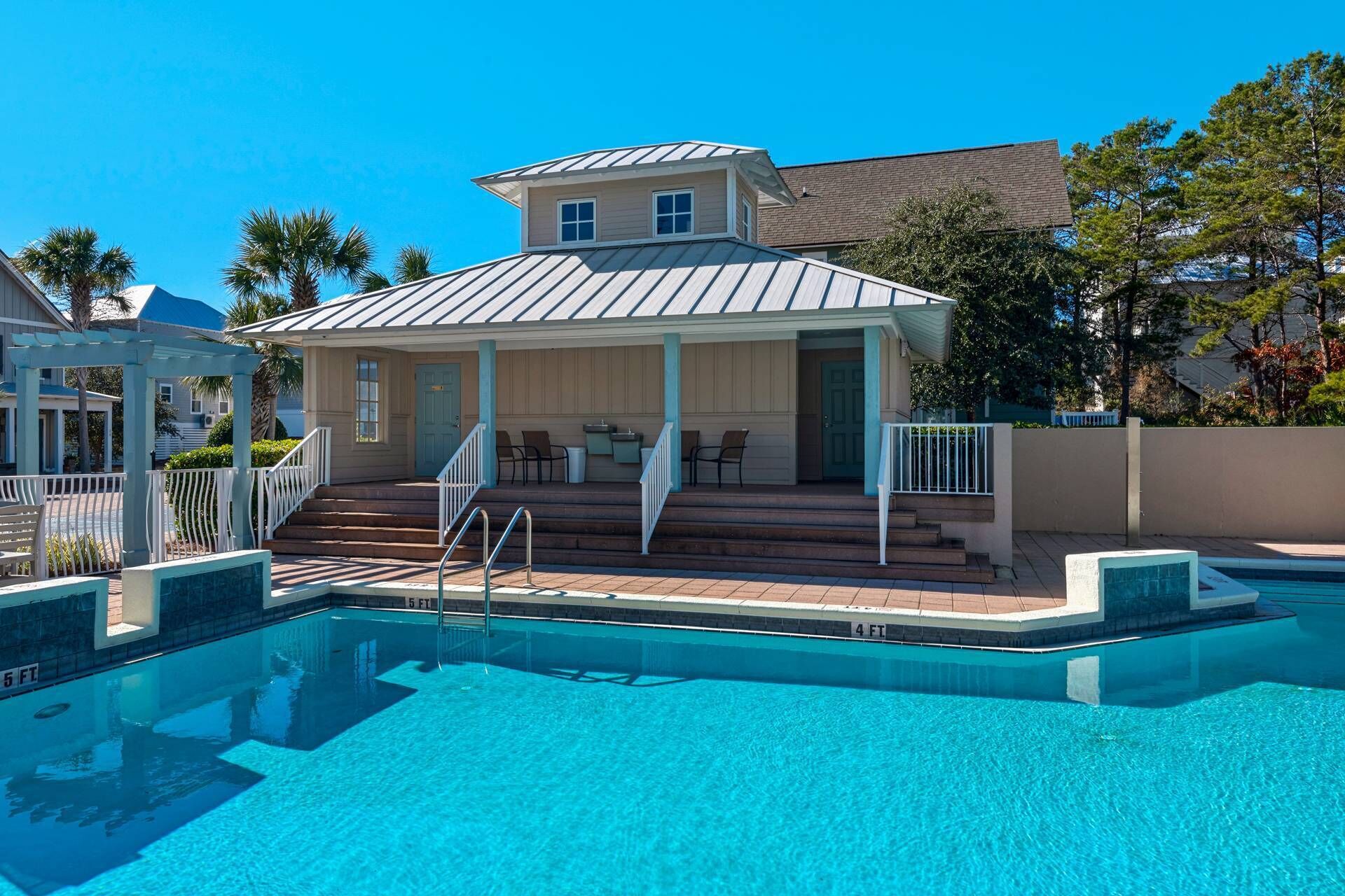 Un espace piscine doté d’un coin salon abrité, d’un escalier menant à la piscine et d’une eau d’un bleu cristallin.