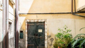 A courtyard with a tiled floor, a closed black door, and potted plants. - Cà Formosa (Venice)
