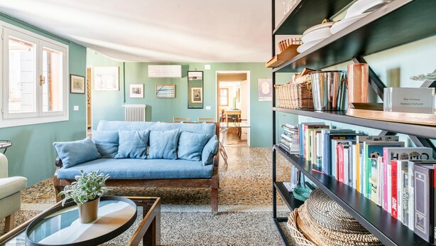 A cozy living room with a blue sofa, a coffee table with a plant, and a bookshelf filled with books. - Cà Formosa (Venice)