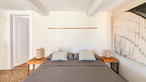A bedroom with a bed, two bedside tables, a lamp, and a wall art piece. - Cà Formosa (Venice)