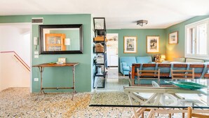 A living room with a glass table, a blue sofa, and a bookshelf. - Cà Formosa (Venice)