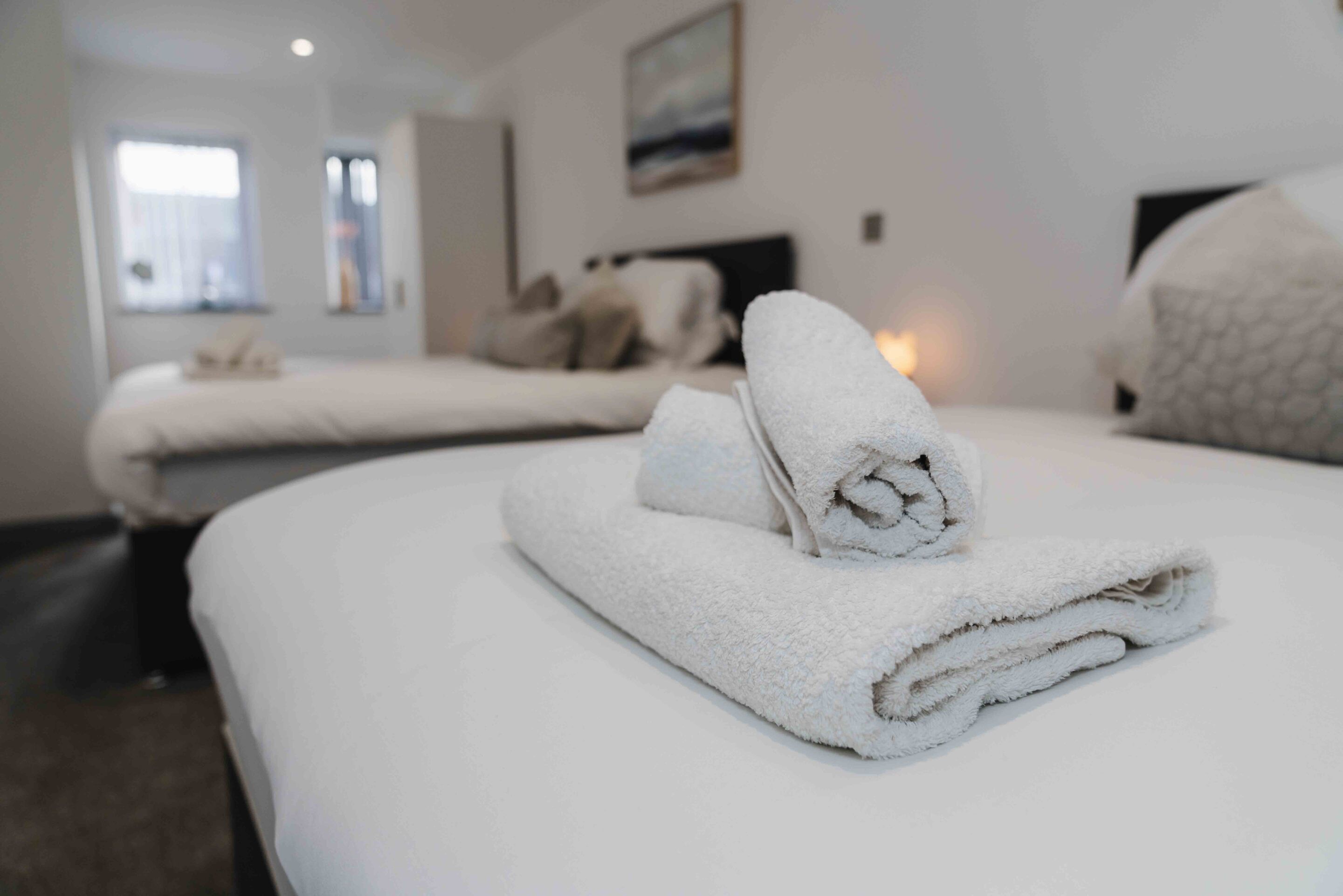 A hotel room with two beds, each with a neatly folded white towel.