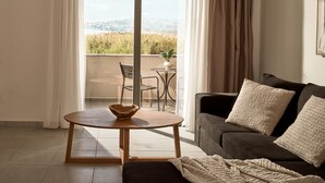 A living room with a sofa, a coffee table, and a view of a balcony with a chair and a table.