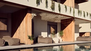 A modern poolside area with a clear pool, wooden deck, and seating.