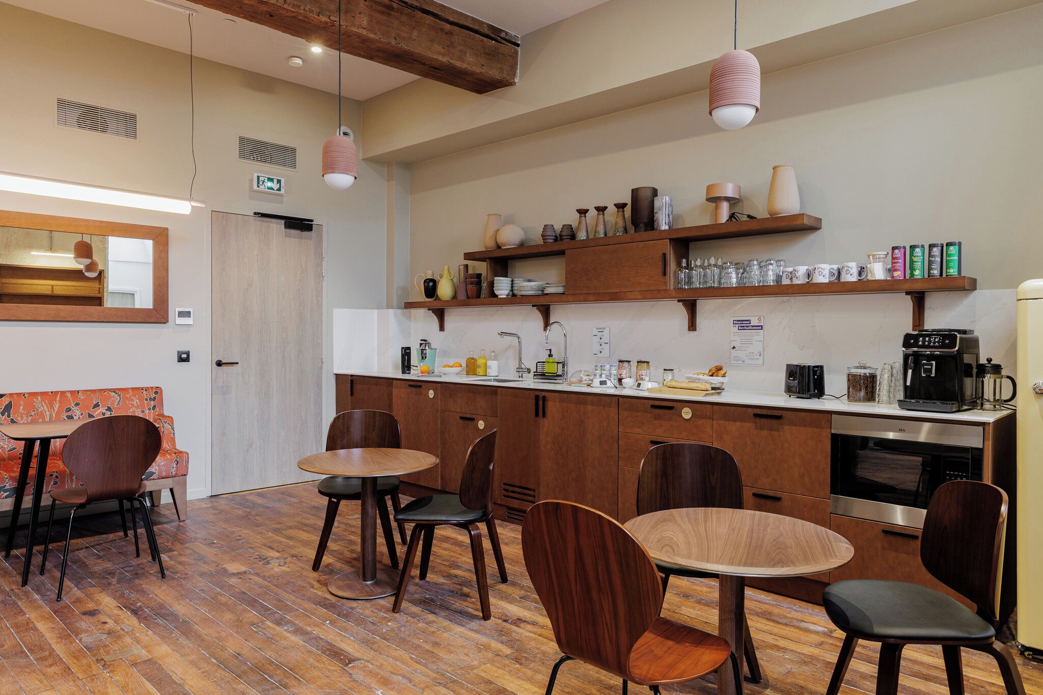 A modern kitchen with wooden cabinets, a countertop, and various kitchen appliances. There are chairs and a table in the dining area.