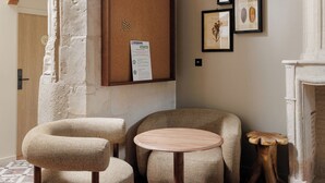 Una sala de estar acogedora con una mesa redonda de madera, dos sillones trenzados, una lámpara colgante y una chimenea.