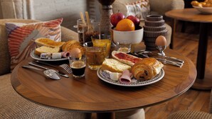Una mesa de desayuno con croissants, pan, huevos y fruta.
