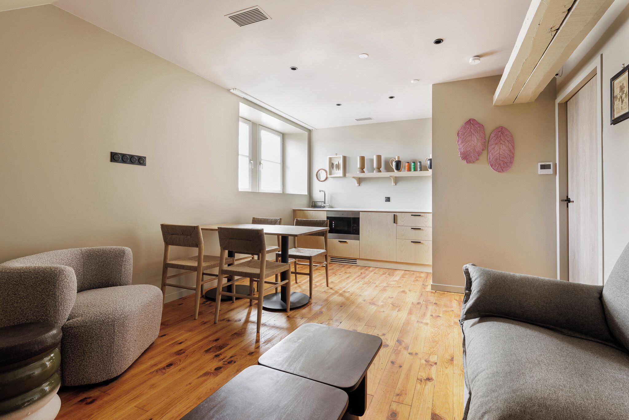 Una sala de estar moderna con comedor, piso de madera y una cocina al fondo.