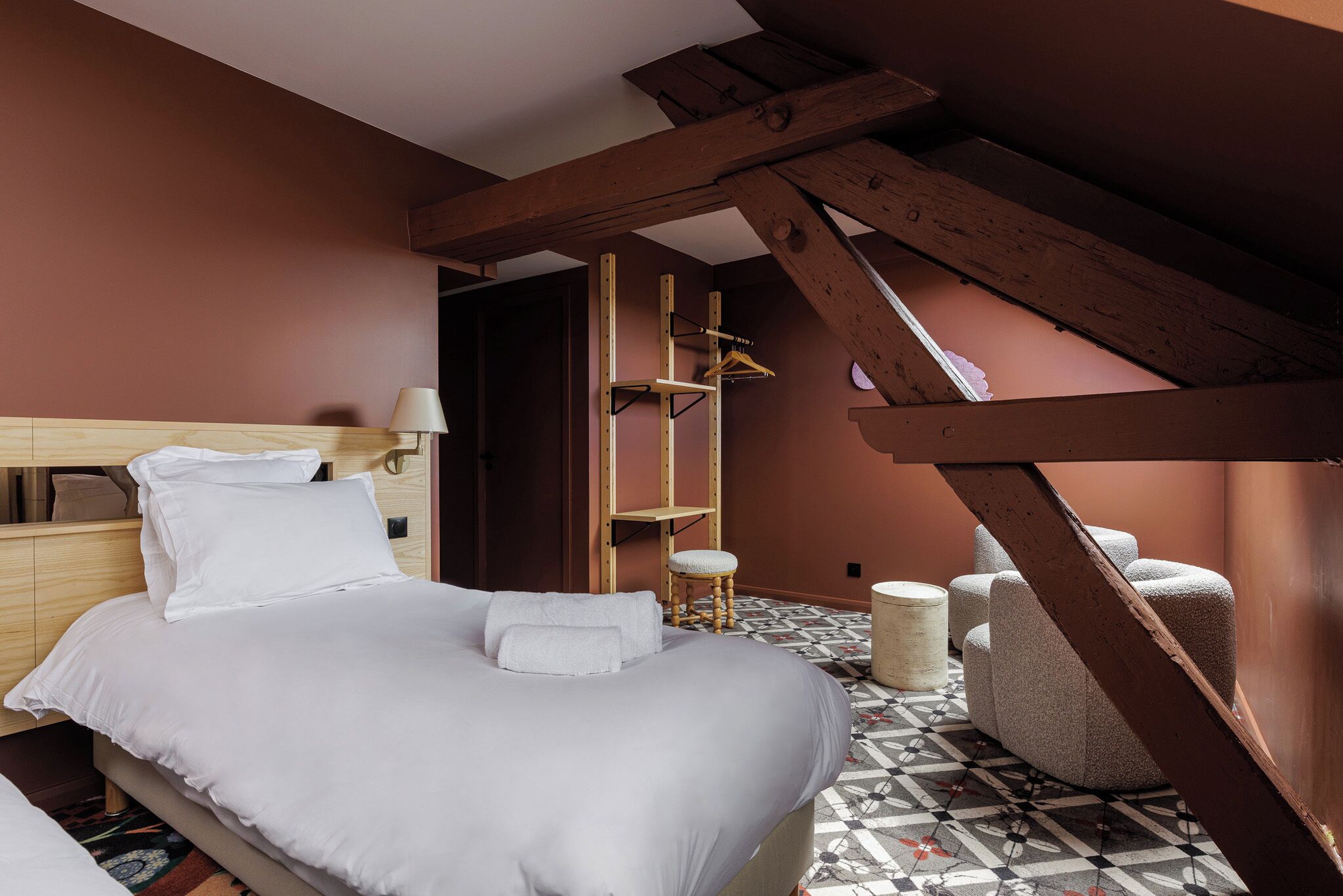 Une chambre à coucher avec un lit, une échelle en bois, une chaise et un petit tabouret.