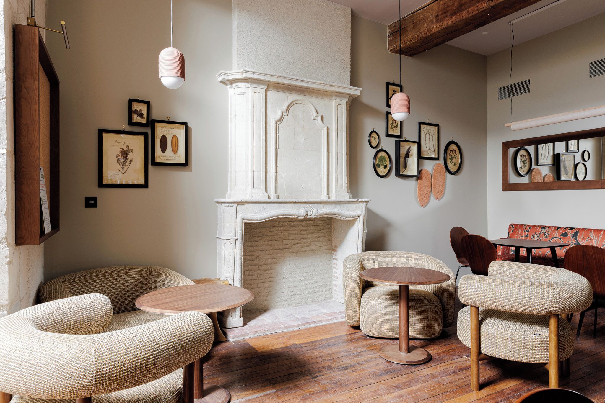 A cozy room with a fireplace, wicker furniture, and framed botanical prints on the walls.